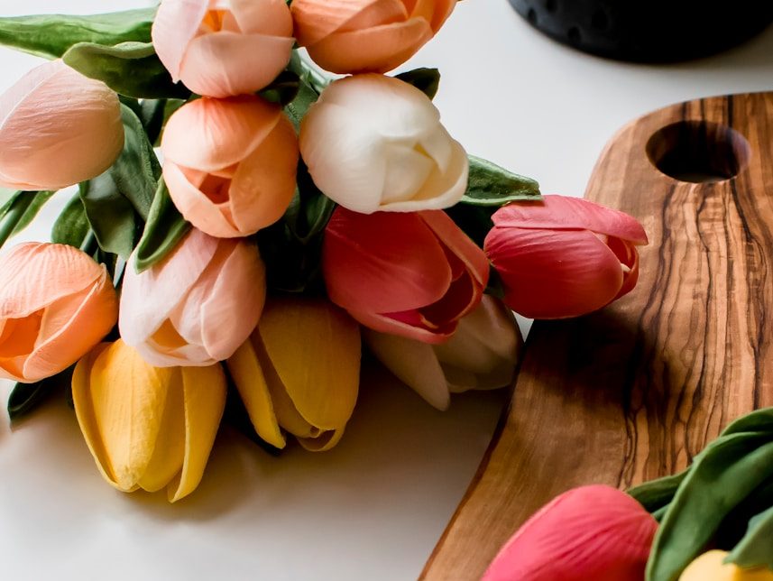 yellow and red tulips on brown wooden chopping board